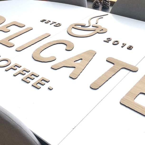Udskæring af logo i træ til Delicate Coffee. Anvendt lys eg.