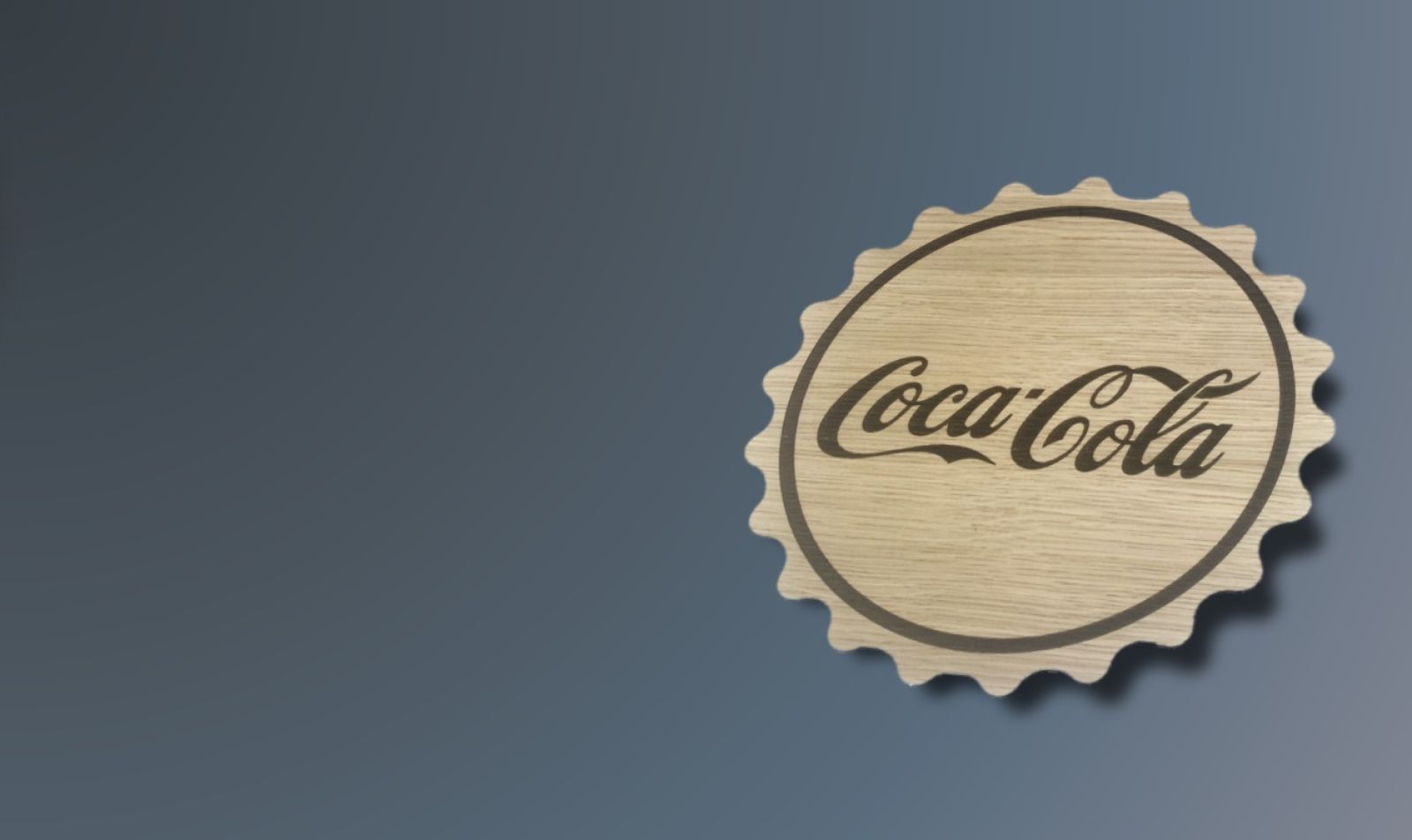 Gravering af Coca Cola logo i i træ. Formet som en kapsel.