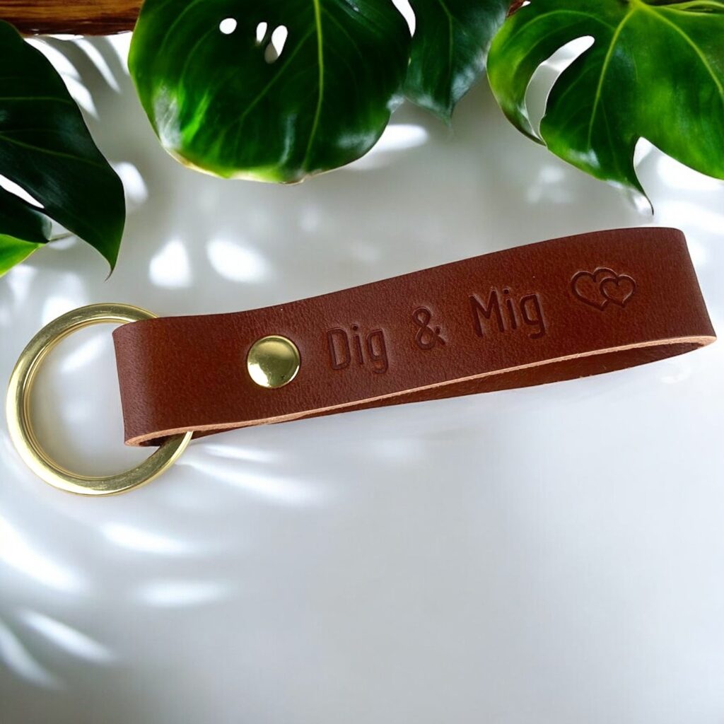 Nøglering i cognac farvet læder med tryk. Der står Dig & Mig og et dobbelthjerte symbol. Messing ring og nitte.