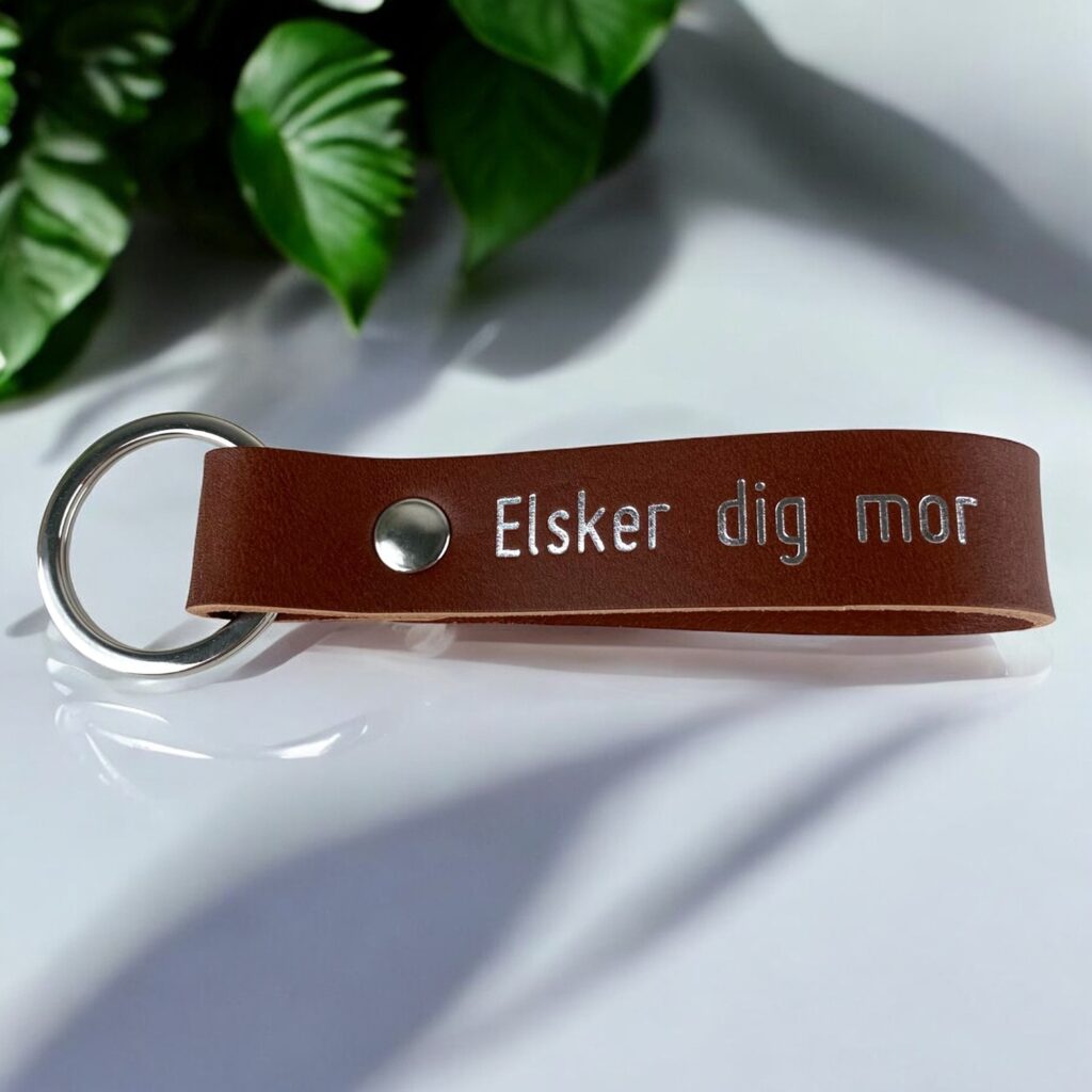 Nøglering i cognac farvet læder med personlig tekst i sølv. Der står Elsker dig mor.