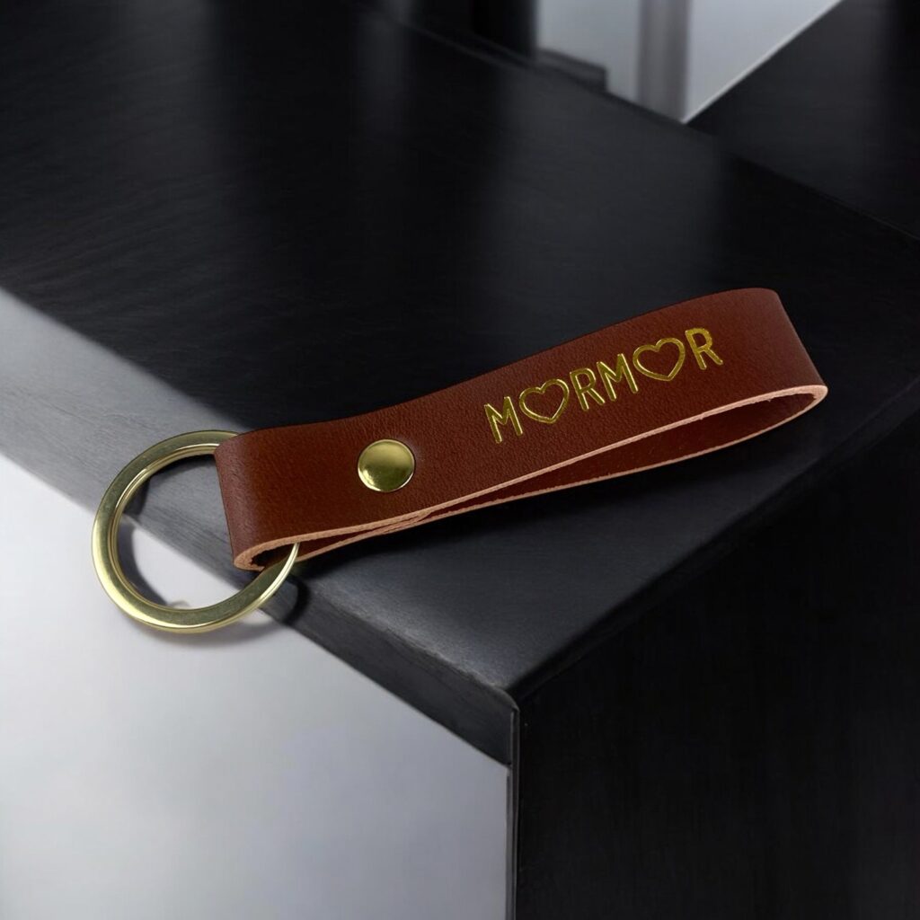 Cognac nøglering med teksten MORMOR i guld. O'erne er erstattet med hjerter. Messing ring og nitte.
