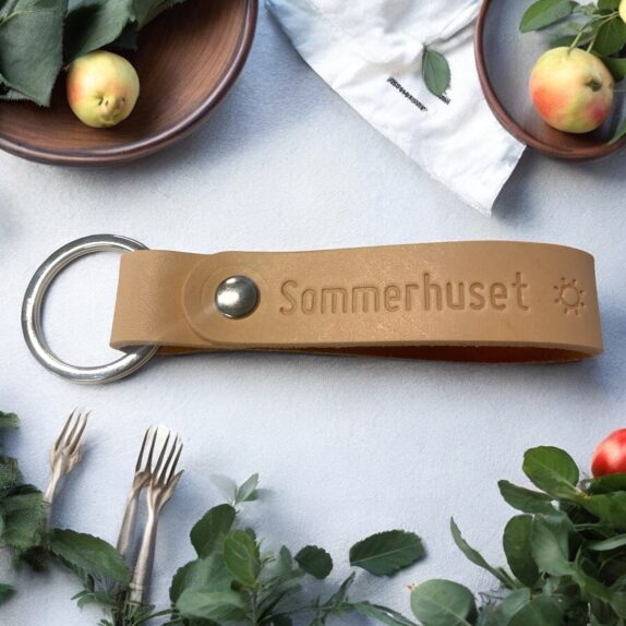 Nøglering i natur læder med personlig og sølv nitte. Der står Sommerhuset og et sol symbol.