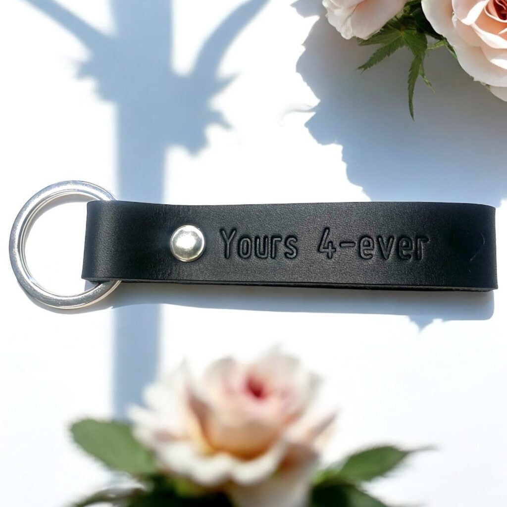 Nøglering i sort læder med tryk og sølv nøglering og nitte. Der står Yours 4-ever