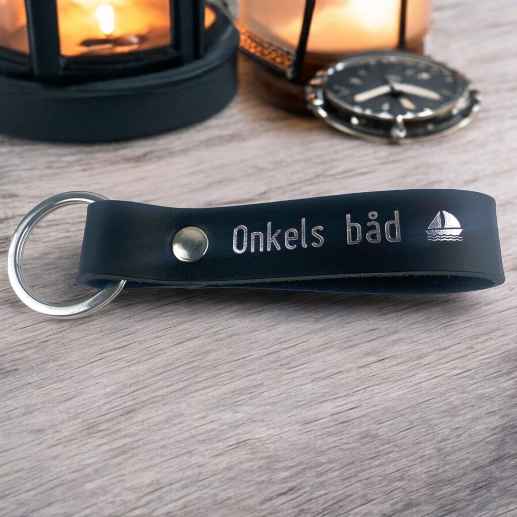Nøglering i sort læder med tryk og sølv nøglering og nitte. Der står Onkels båd og et båd symbol.