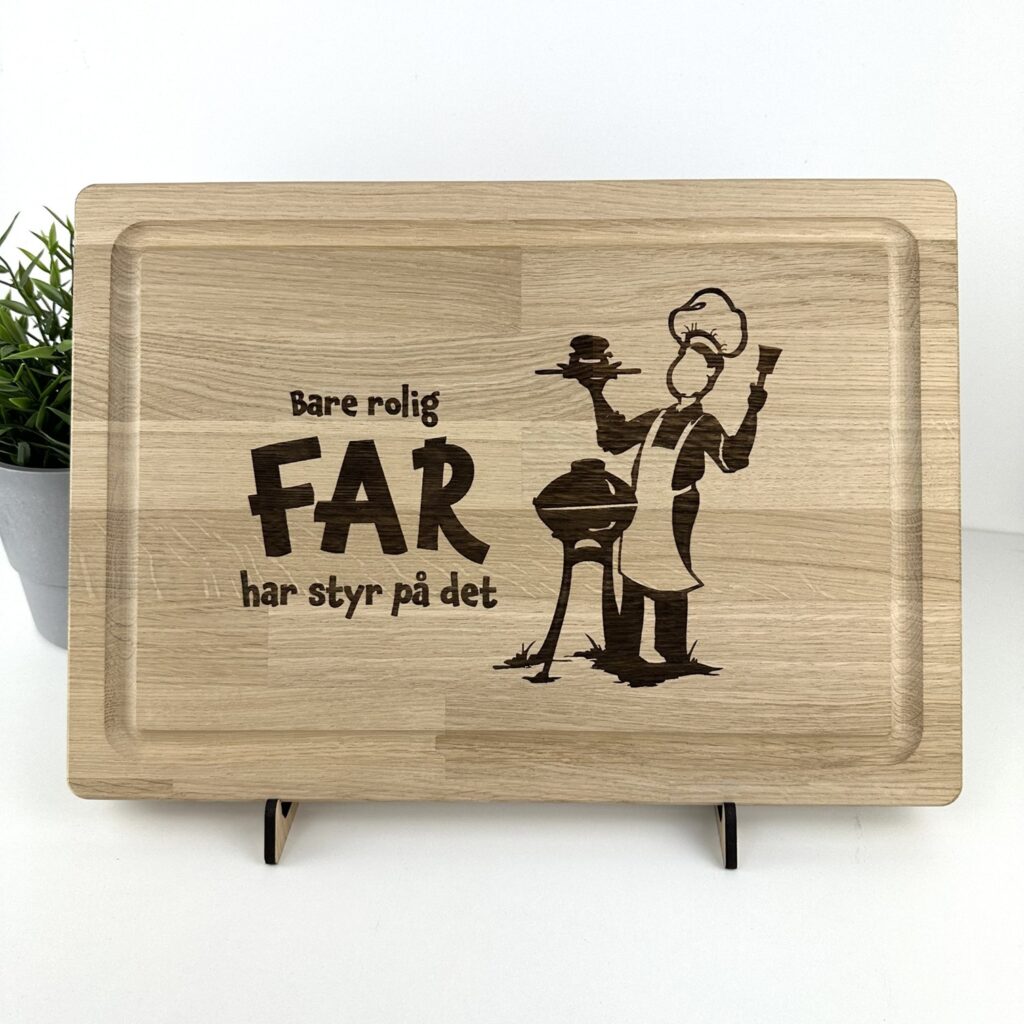 Skærebræt i massiv eg med teksten Bare rolig - Far har styr på det. Teksten er graveret sammen med far der står ved grillen.