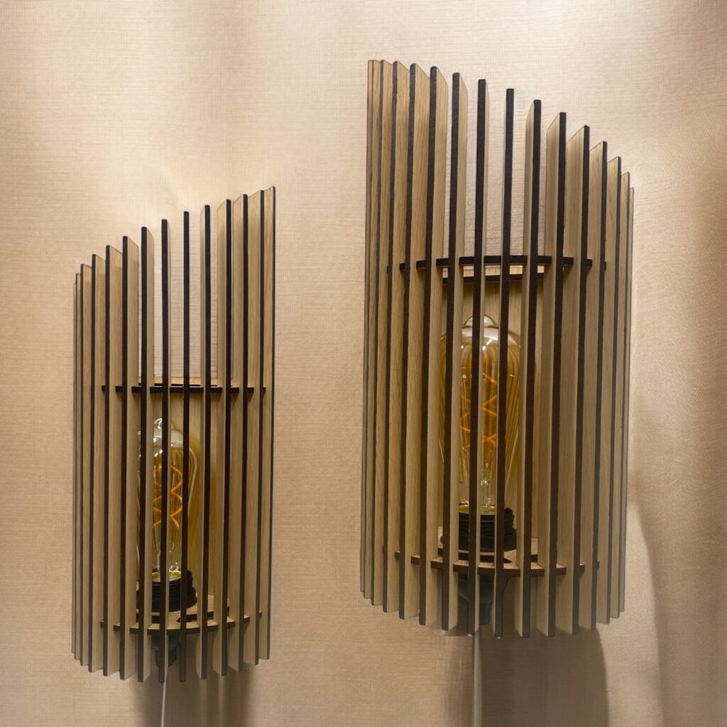 To Twister væglamper lavet med lameller i træ. Lamperne er slukket.