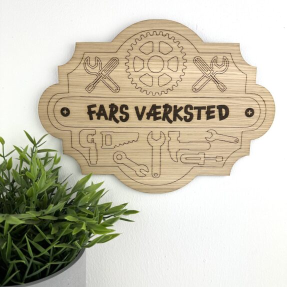 Skilt i træ med graveret værktøj og teksten Fars Værksted.