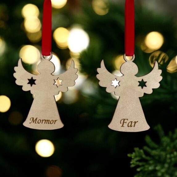 To engle med navn i træ. En med Mormor og en med Far. Englene hænger i rødt silkebånd på et juletræ.